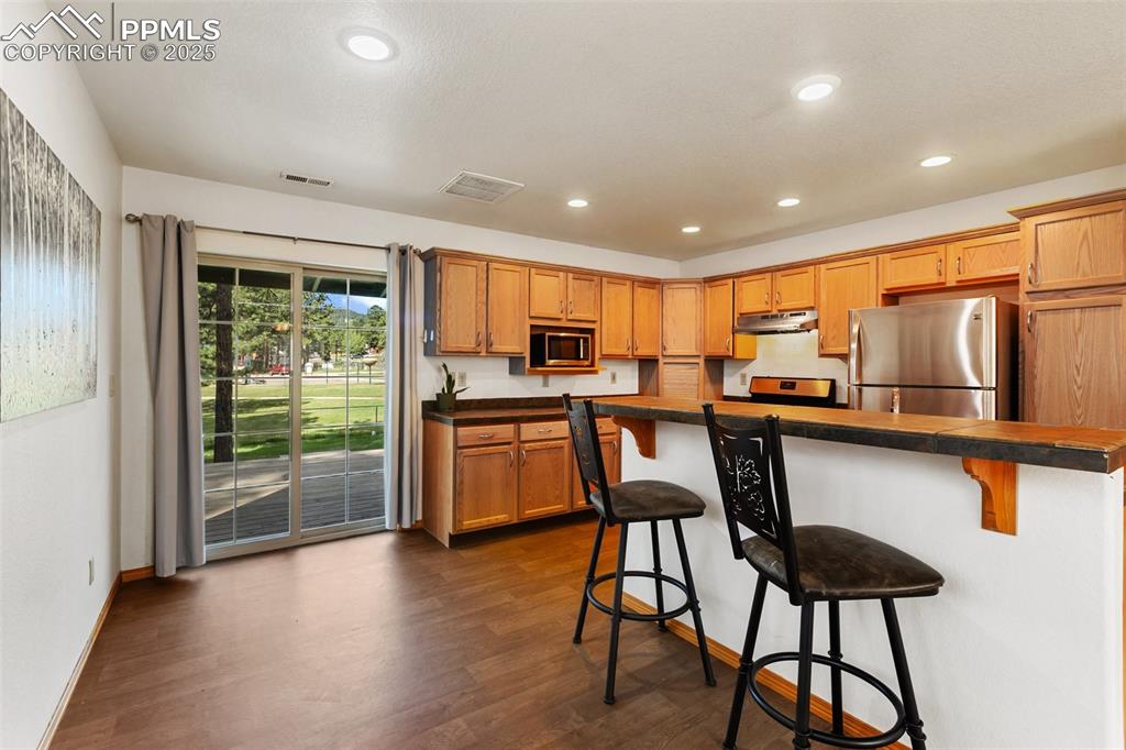 Image 8 of 30: Kitchen featuring a kitchen breakfast bar, appliances with stainless steel 
