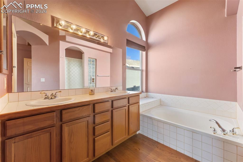 Image 16 of 34: Bathroom with double vanity, light wood-style floors, and a bath