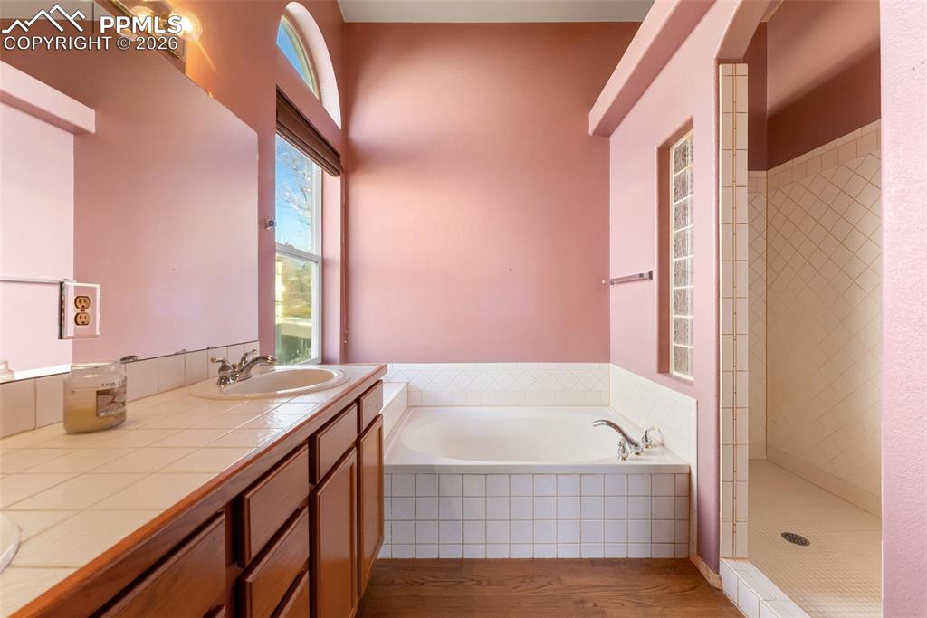 Image 17 of 34: Full bath featuring a shower stall, a garden tub, wood finished floors, and