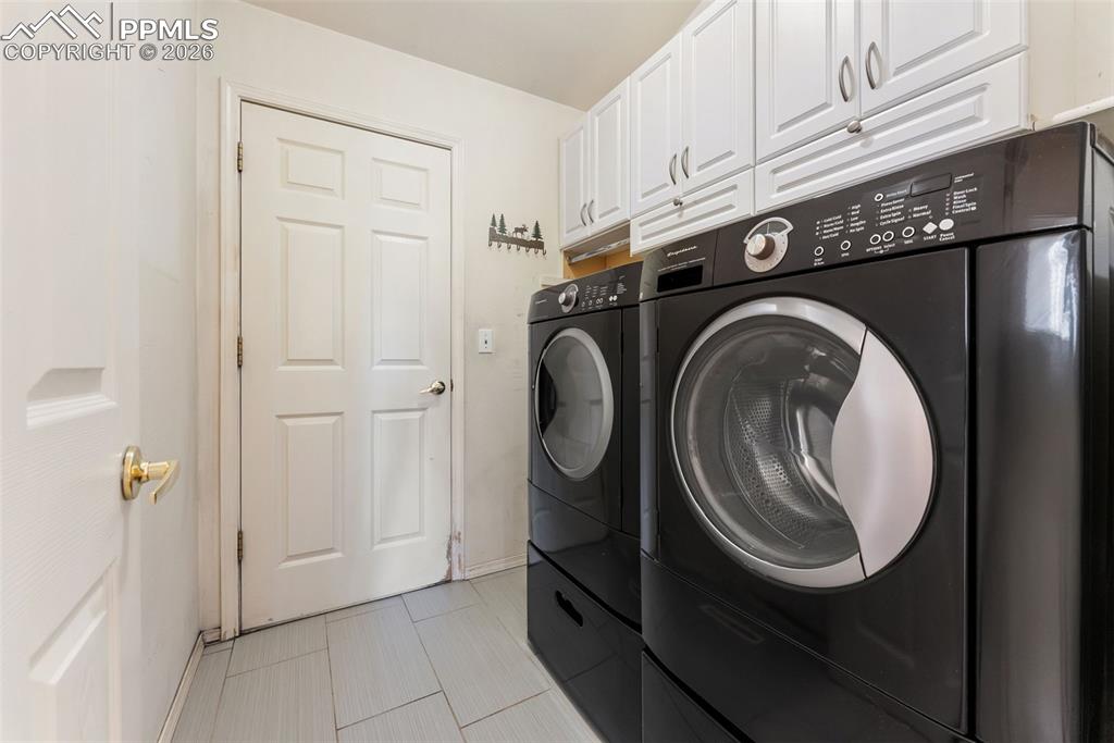 Image 18 of 34: Washroom featuring washer and clothes dryer and cabinet space