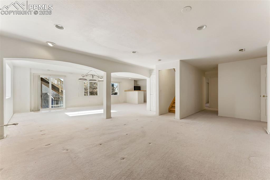 Image 22 of 34: Unfurnished living room featuring arched walkways, stairs, and carpet