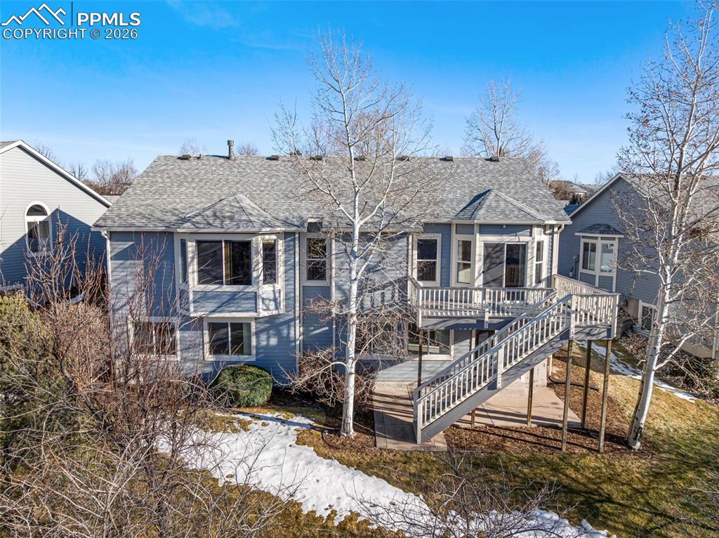 Image 34 of 34: View of front facade with a shingled roof, a wooden deck, and stairway