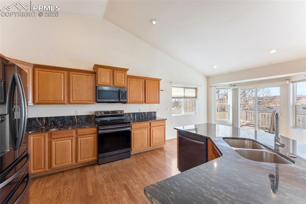 Image 8 of 34: Kitchen with stainless steel range with electric cooktop, dark stone counte