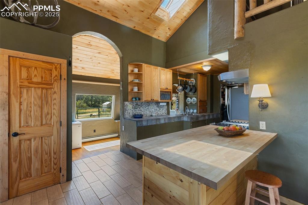 Image 15 of 50: Archway into the sunroom from the kitchen. Kitchen breakfast bar.