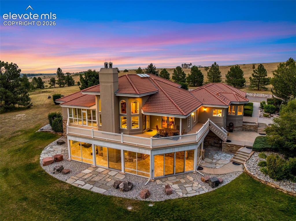 Caption: Multi-level residence featuring a clay tile roof, expansive outdoor decking, and a lower-level patio