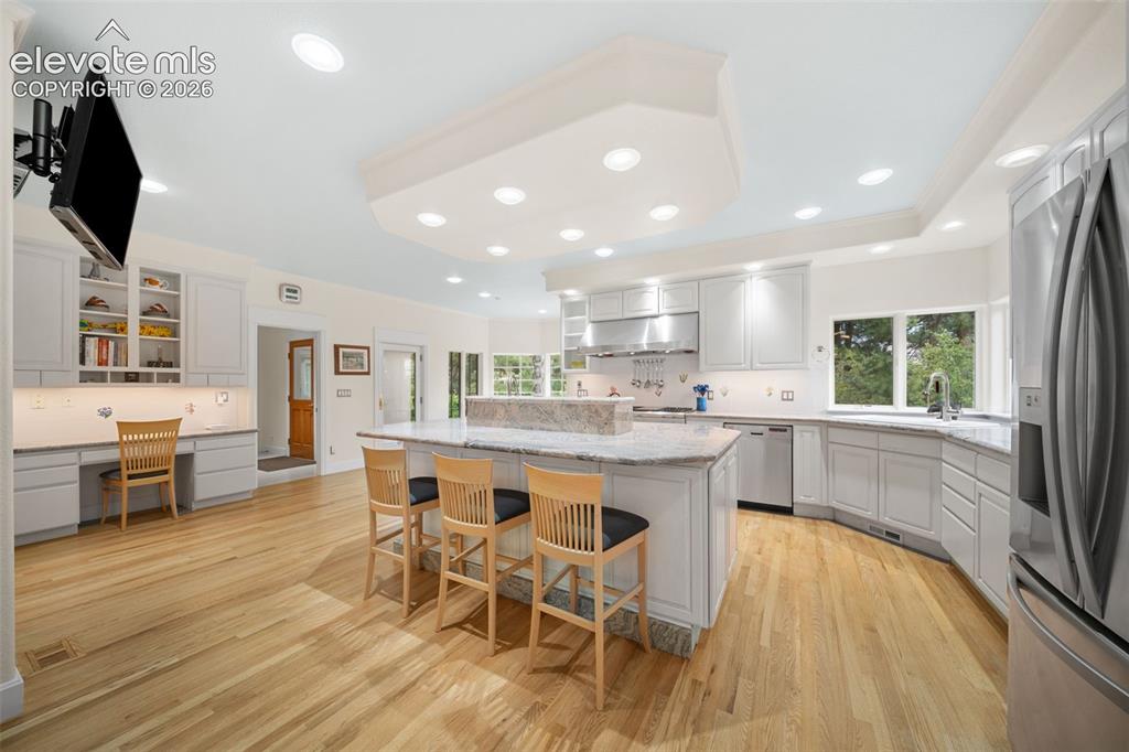 Image 14 of 50: Recessed lighting illuminates the kitchen featuring wood-finish flooring, w