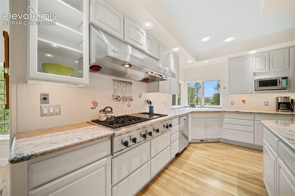 Image 16 of 50: Kitchen featuring light wood-finish flooring, white cabinetry, a large rang