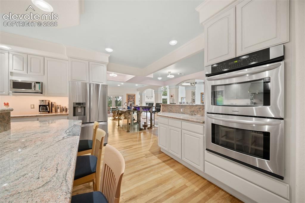 Image 17 of 50: Kitchen featuring light-toned cabinetry, stainless steel appliances, granit