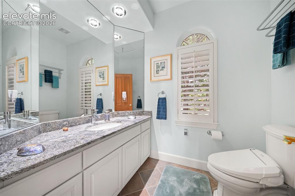 Image 21 of 50: Dual vanity with granite countertop, integrated sinks, full-height mirror,