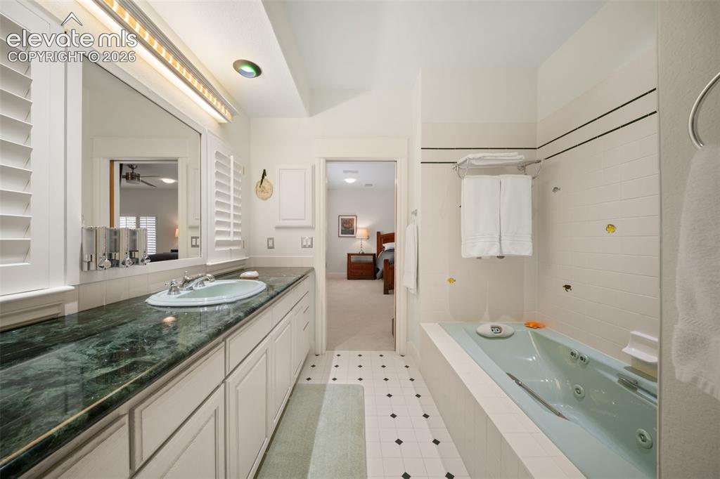 Image 25 of 50: Elongated vanity with a dark green stone countertop, integrated sink, and w