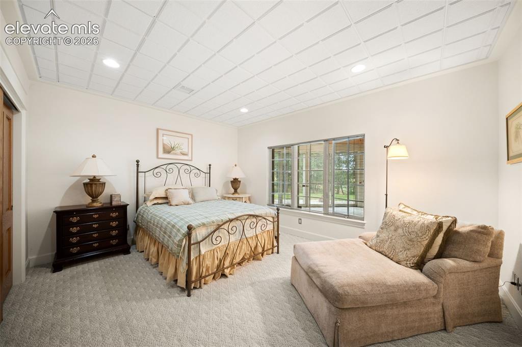 Image 33 of 50: Spacious primary bedroom suite featuring a decorative metal bed frame, wood