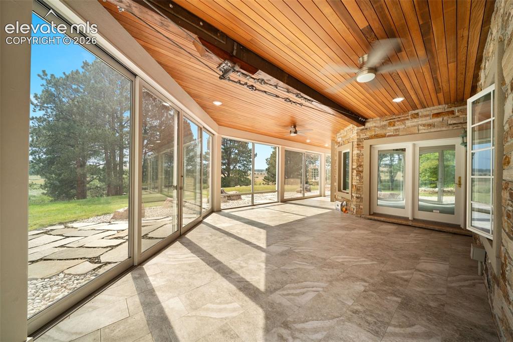 Image 36 of 50: Enclosed patio featuring a wood-paneled ceiling, ceiling fan, and tiled flo