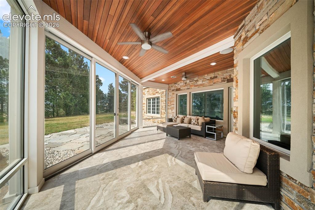 Image 37 of 50: Covered patio featuring an exposed wood plank ceiling, multiple ceiling fan