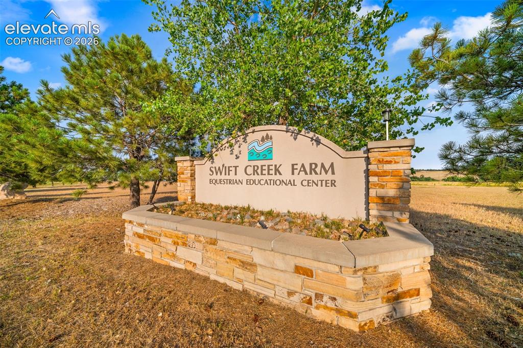 Image 38 of 50: Stone-clad entry sign featuring integrated landscaping and surrounding matu