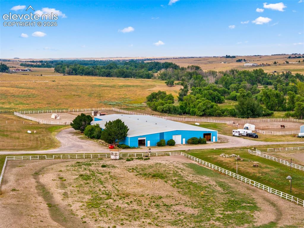 Image 44 of 50: Expansive property featuring a large blue building, multiple fenced enclosu