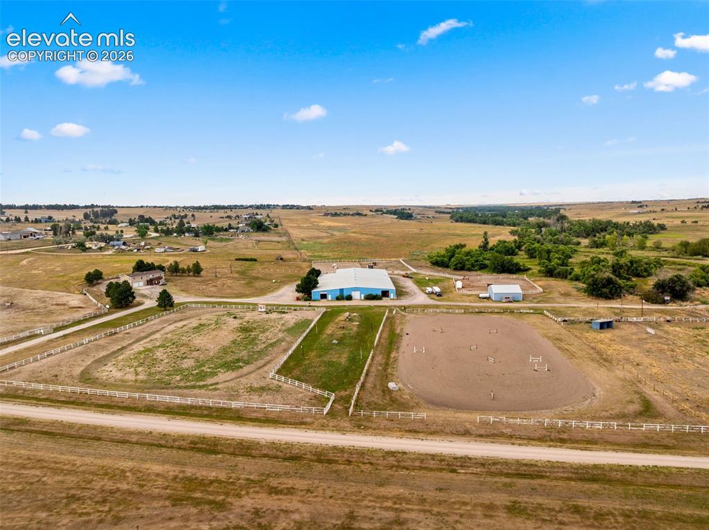 Image 45 of 50: Expansive property featuring a large blue outbuilding, a smaller silver out