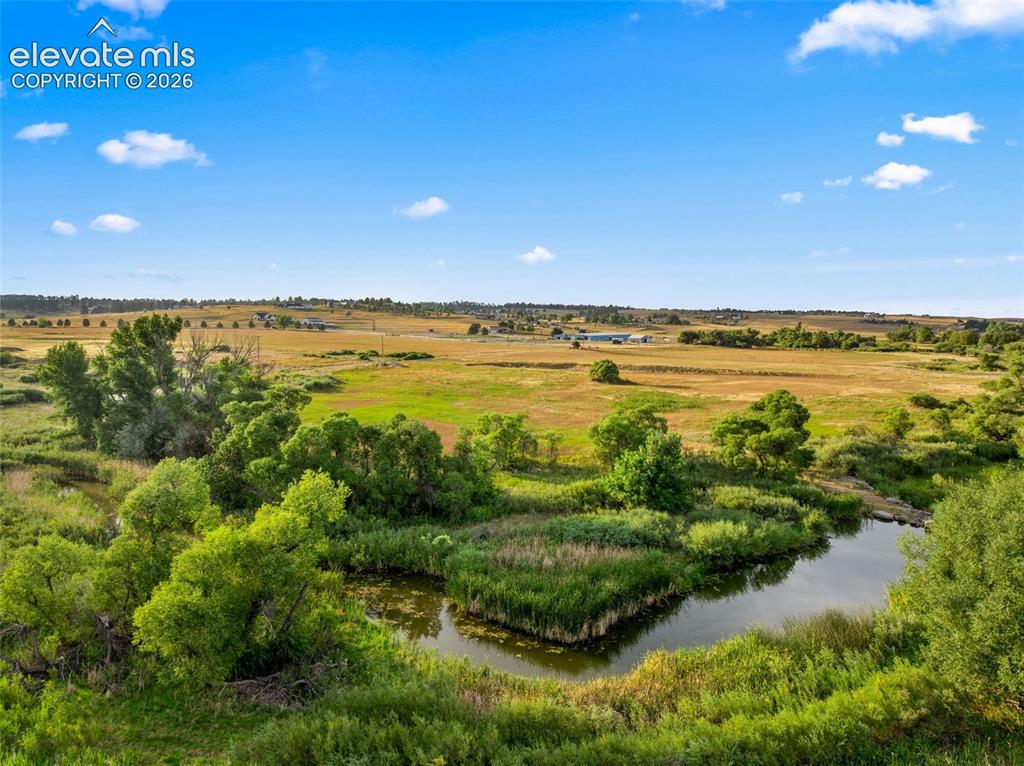 Image 48 of 50: Expansive natural landscape featuring a meandering water body, abundant gre