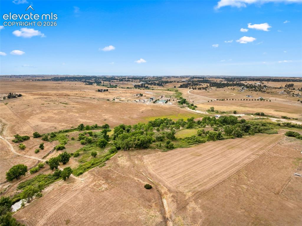 Image 50 of 50: Expansive property featuring undeveloped land, scattered trees, and distant