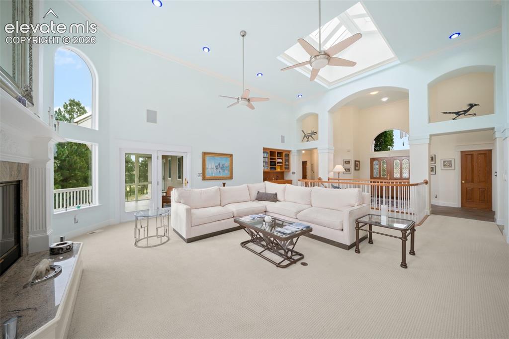 Image 8 of 50: Expansive great room featuring soaring ceilings with skylight, ceiling fan,