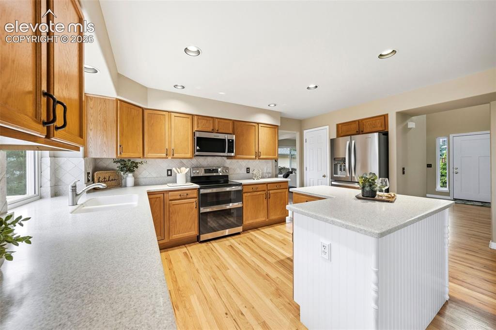 Image 10 of 50: Kitchen featuring wood cabinetry, stainless steel appliances, and a central