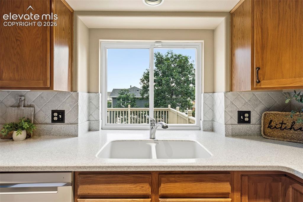Image 11 of 50: Kitchen featuring a double basin sink, light-toned countertops, and a tiled