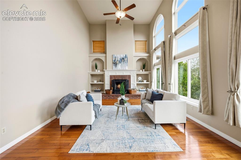 Image 15 of 50: Two-story living area featuring a brick fireplace with mantel, built-in she