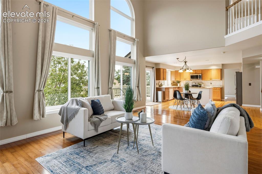 Image 17 of 50: Two-story living area featuring wood-finish flooring, abundant natural ligh