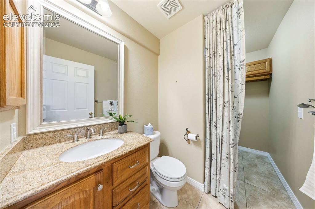 Image 19 of 50: Bathroom vanity featuring a polished stone countertop, undermount sink, and