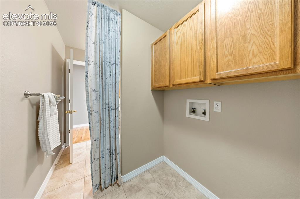 Image 20 of 50: Utility area featuring light wood-finish cabinetry and neutral wall tones