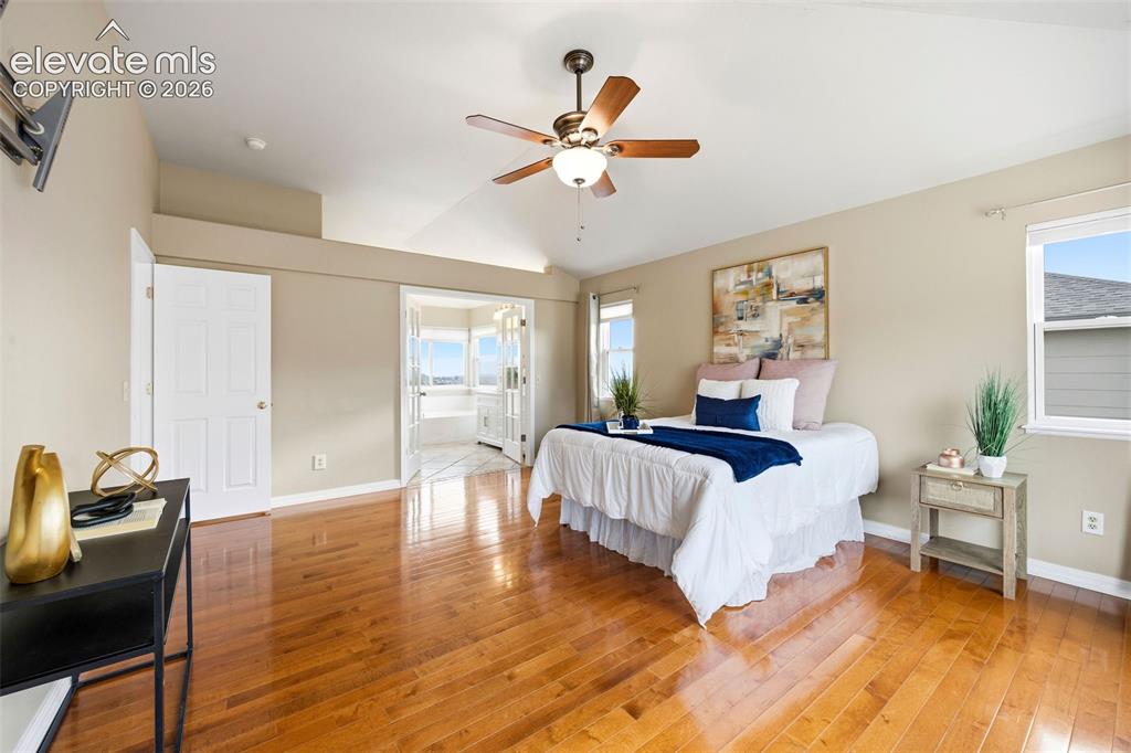 Image 23 of 50: Spacious room with wood-finish flooring, vaulted ceilings, and a ceiling fa