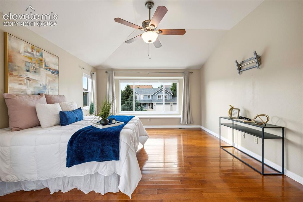 Image 24 of 50: Spacious room featuring vaulted ceilings, wood-finish flooring, a ceiling f