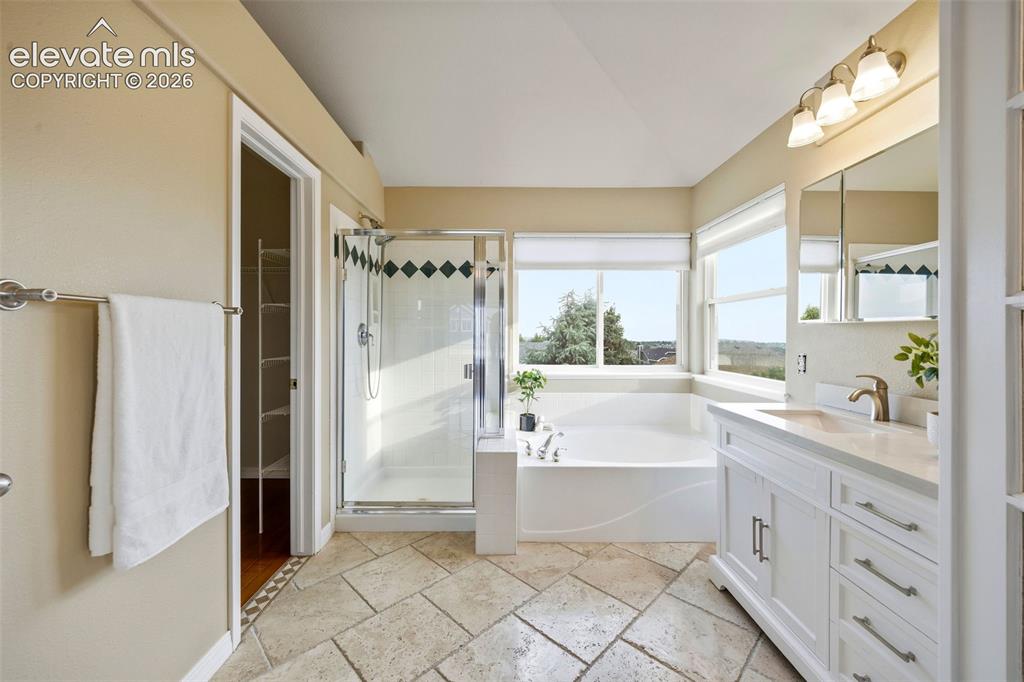 Image 25 of 50: Bathroom featuring large format tile flooring, a built-in soaking tub, a gl