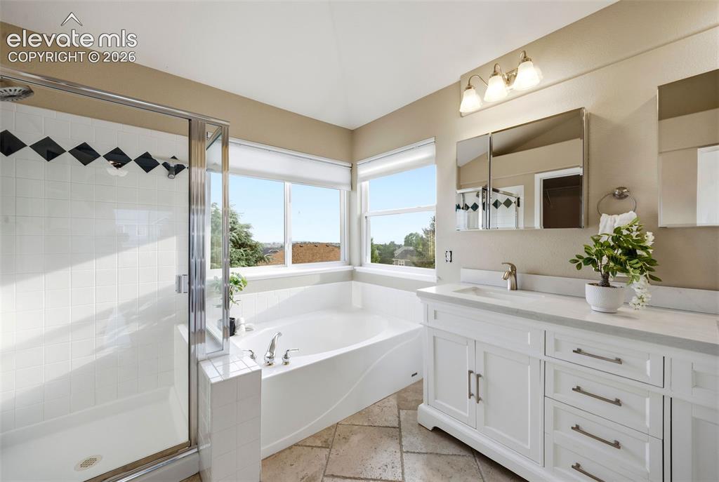 Image 26 of 50: Bathroom featuring a soaking tub, separate shower with glass enclosure, and
