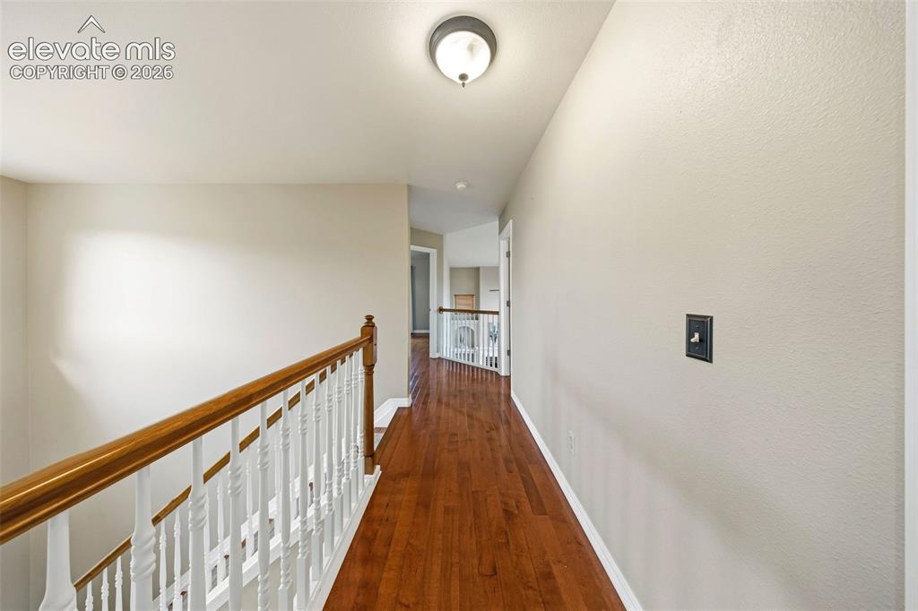 Image 28 of 50: Hallway with wood-finish flooring, white painted walls, and a ceiling-mount