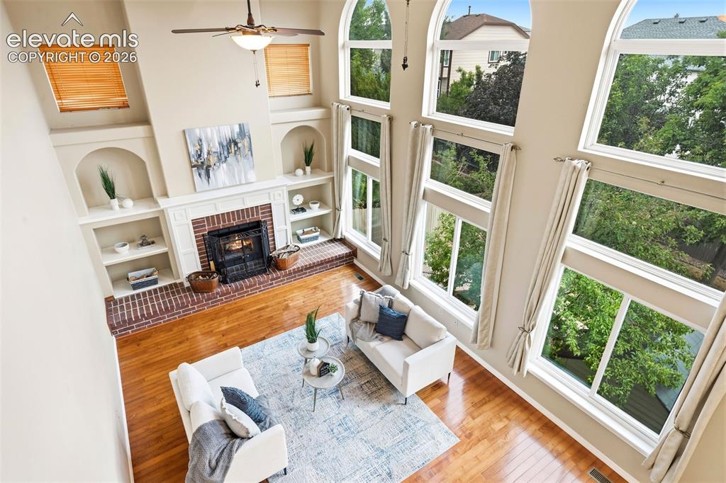 Image 32 of 50: Two-story living area featuring extensive arched windows, a brick fireplace