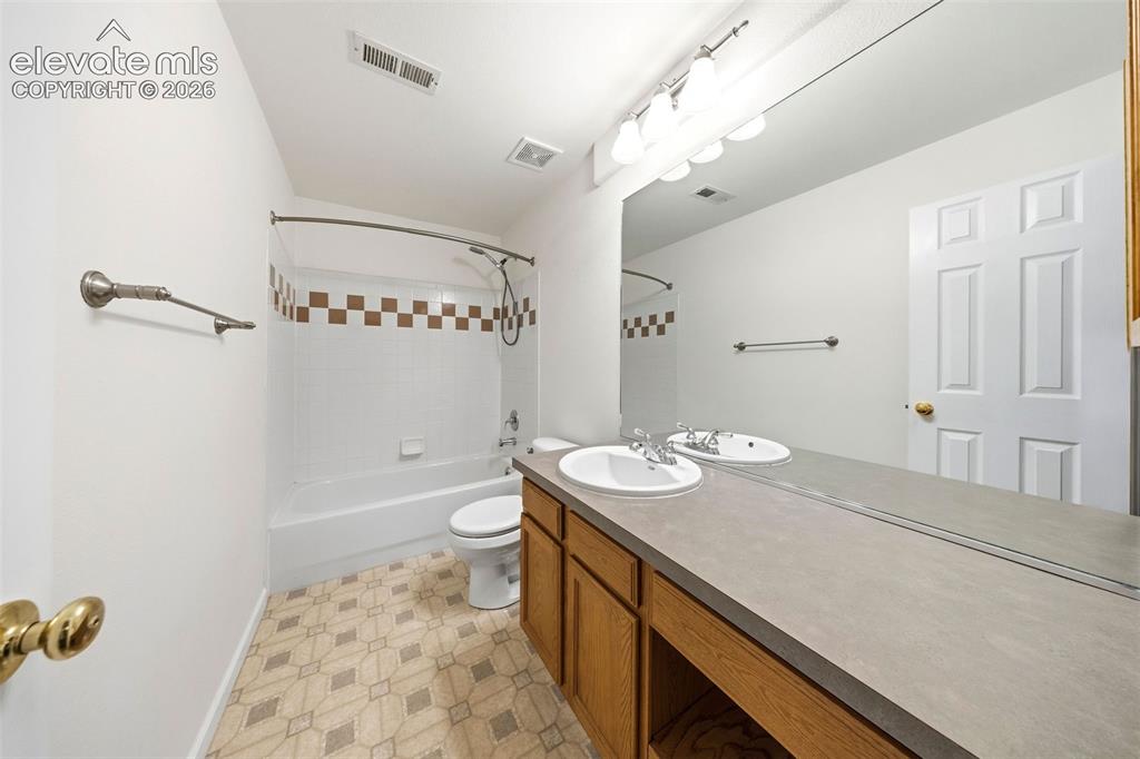 Image 37 of 50: Bathroom featuring a dual-sink vanity with a solid surface countertop, an e