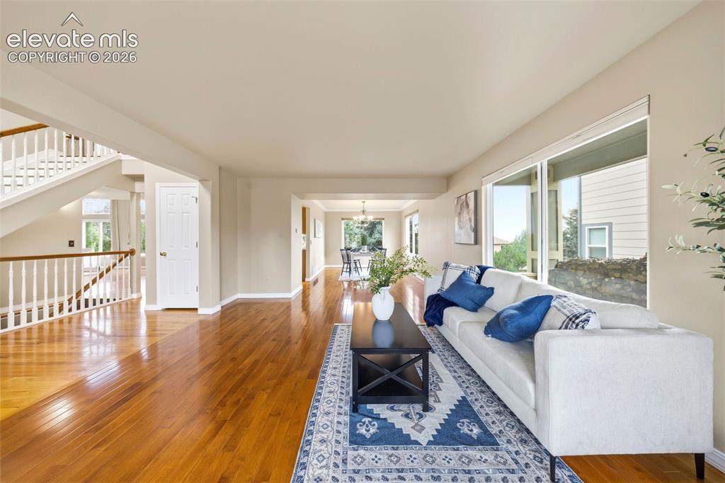 Image 4 of 50: Expansive living room featuring wood-finish flooring, large windows, and a