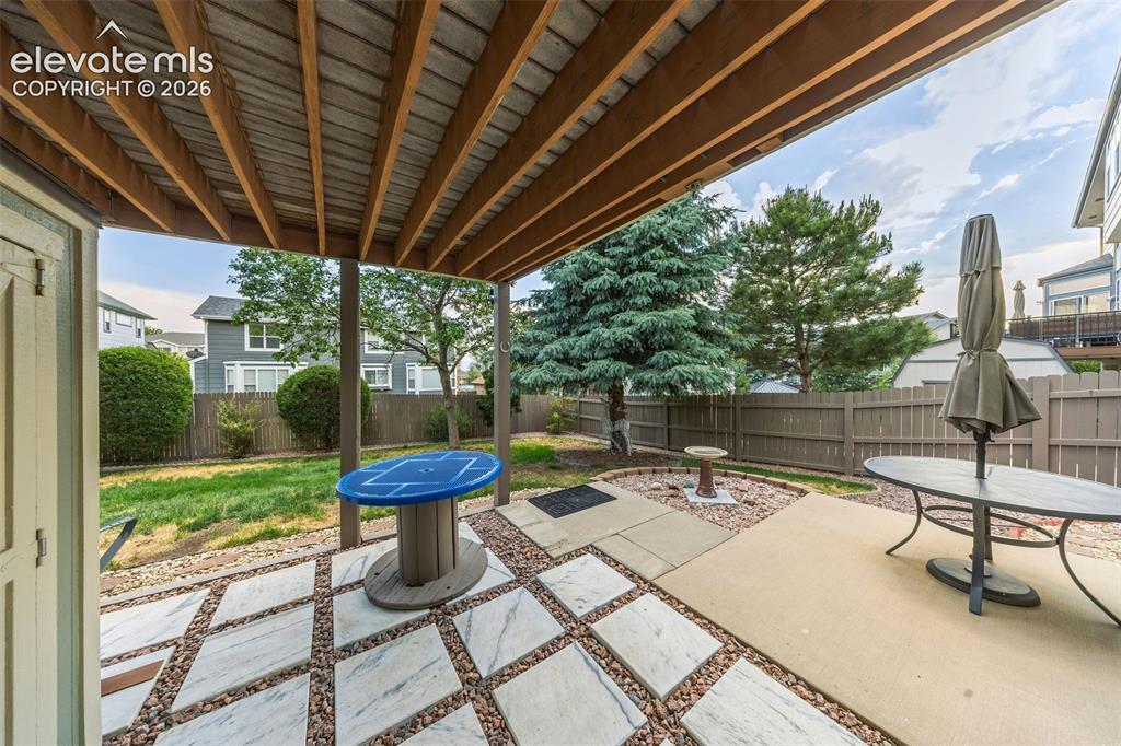 Image 42 of 50: Covered patio featuring a concrete slab and patterned stone tile with grave