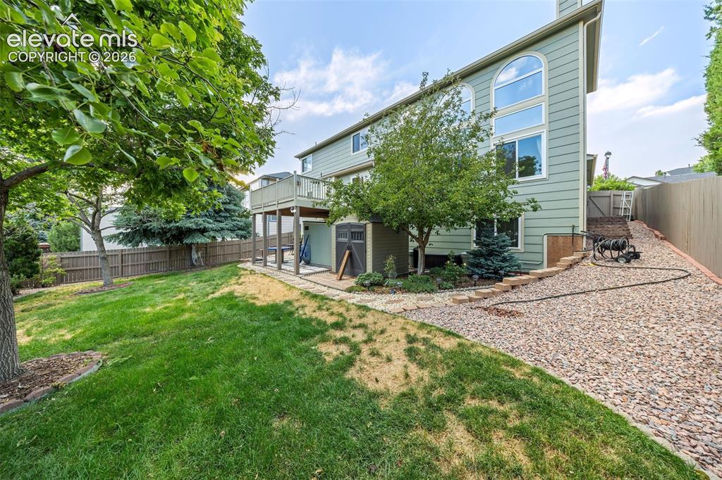 Image 44 of 50: Spacious backyard featuring a multi-level deck, a mature shade tree, a fenc