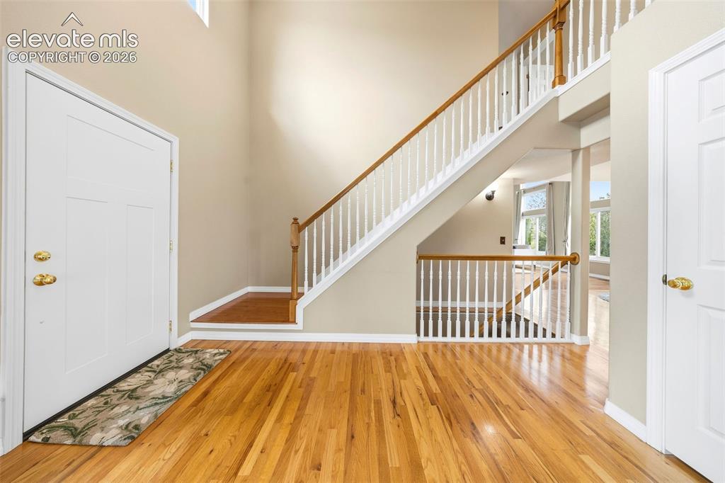 Image 5 of 50: Entryway featuring a two-story foyer, hardwood flooring, and a grand stairc