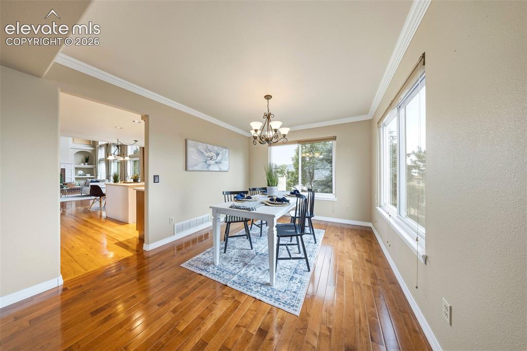 Image 6 of 50: Dining area featuring rich wood-finish flooring, a contemporary chandelier,