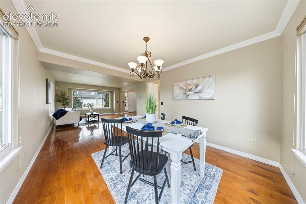 Image 7 of 50: Formal dining area featuring wood-finish flooring, a chandelier, and crown
