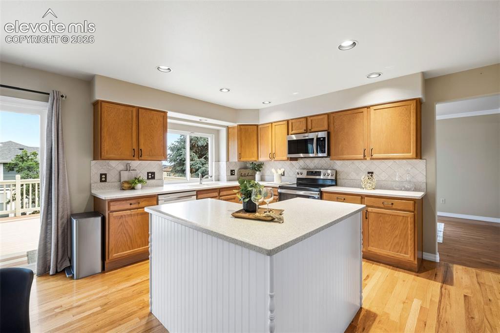 Image 8 of 50: Kitchen featuring wood-finish flooring, recessed lighting, and a center isl