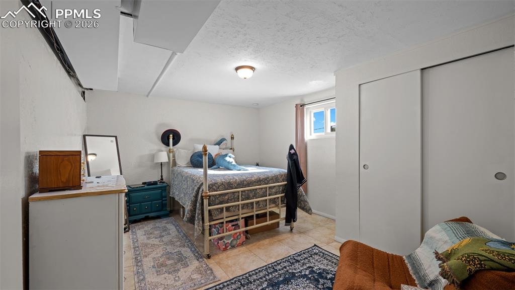 Image 16 of 23: Bedroom featuring a textured ceiling, a closet, and light tile patterned fl