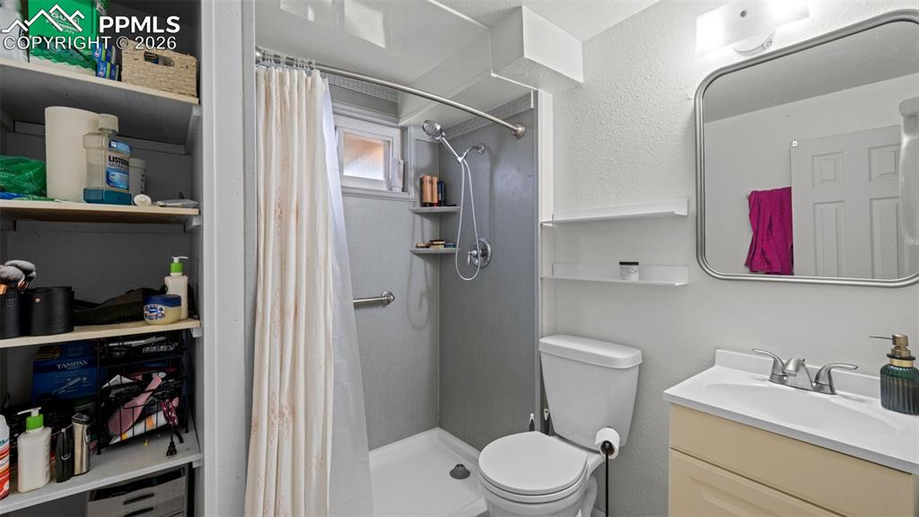Image 17 of 23: Full bath with vanity, a textured wall, and a stall shower