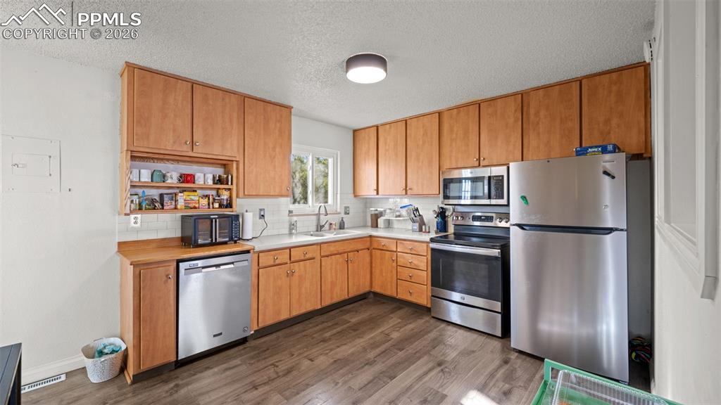 Image 6 of 23: Kitchen featuring stainless steel appliances, dark wood-style flooring, dec