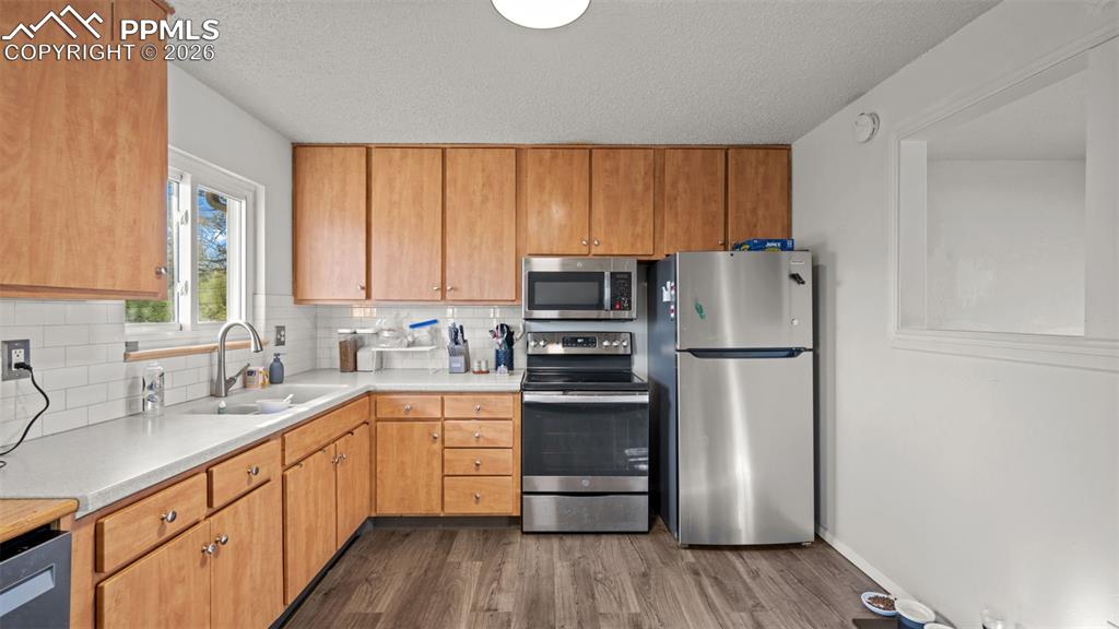 Image 8 of 23: Kitchen with light countertops, stainless steel appliances, decorative back