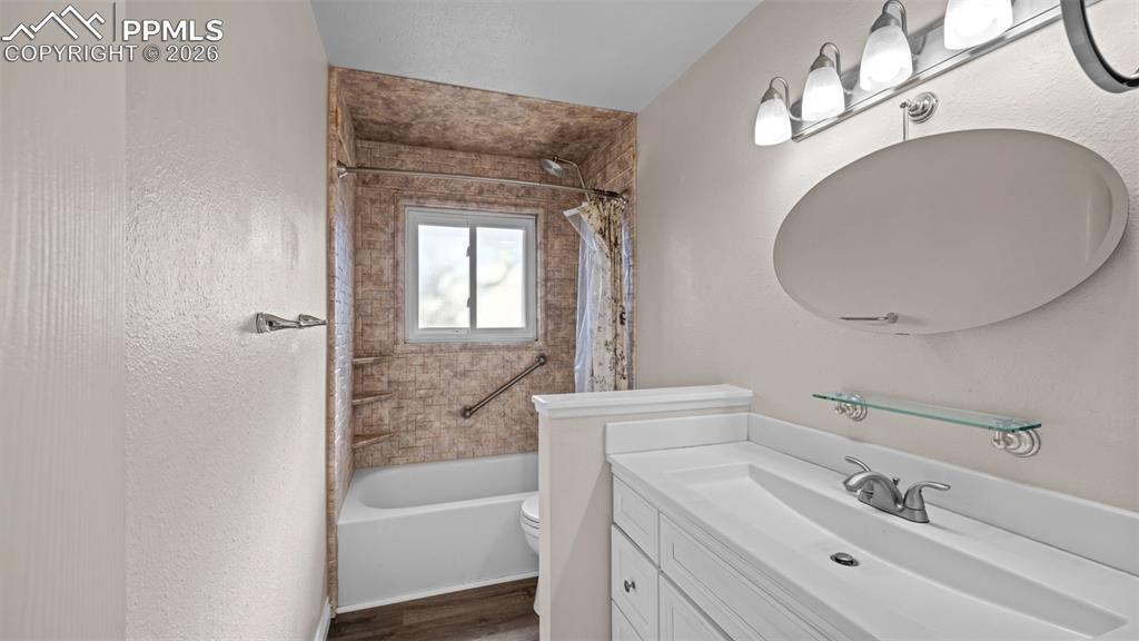 Image 9 of 23: Full bath with vanity, shower / bath combo with shower curtain, a textured