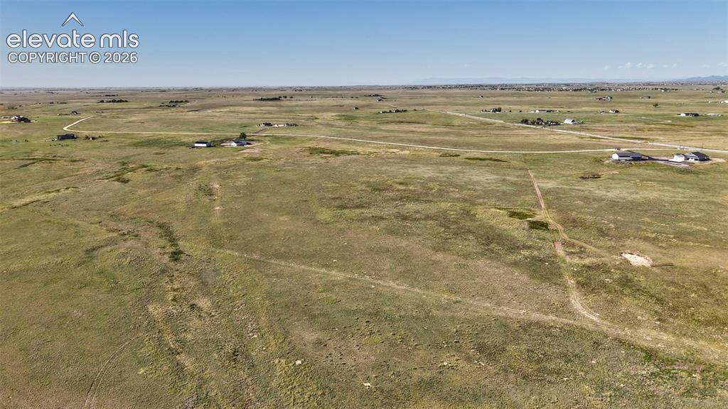Image 6 of 9: Expansive open land featuring natural grasses and distant residential struc