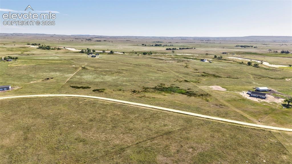 Image 9 of 9: Expansive rural landscape featuring a winding dirt road and distant structu